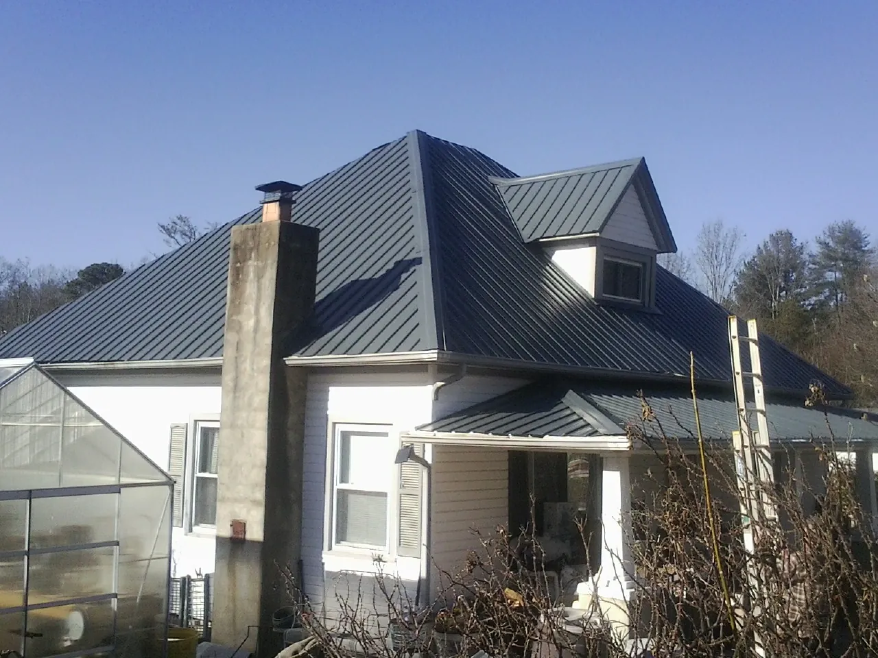 Dark blue standing seam metal roof on a white farmhouse with dormer — Slate & Tile Roof Repair by Roofing Brothers in Elvaston