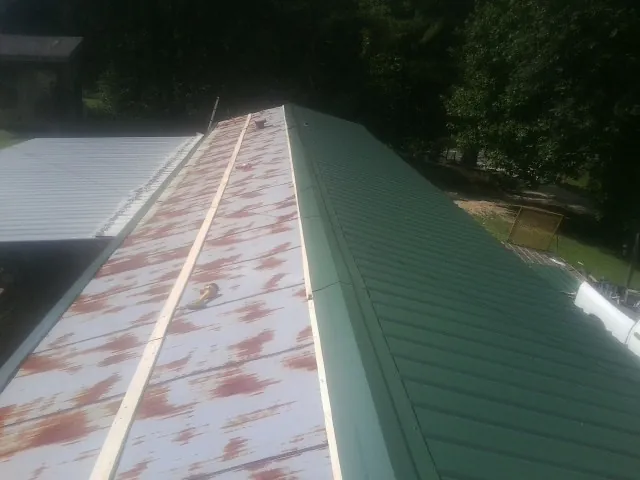 Old rusted panels beside newly installed green metal roofing — Wind Damage Roof Repair by Roofing Brothers in Elvaston