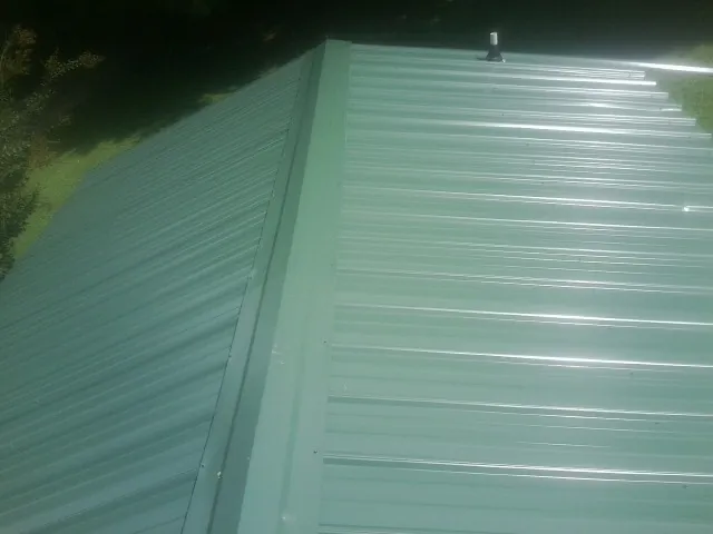New green metal panels meeting at the ridge of a roof — Flat Roof Repair work by our crew in Elvaston