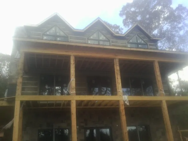 Dormers and porch framing on a large log home under construction — Roof Coating work by our crew in Elvaston