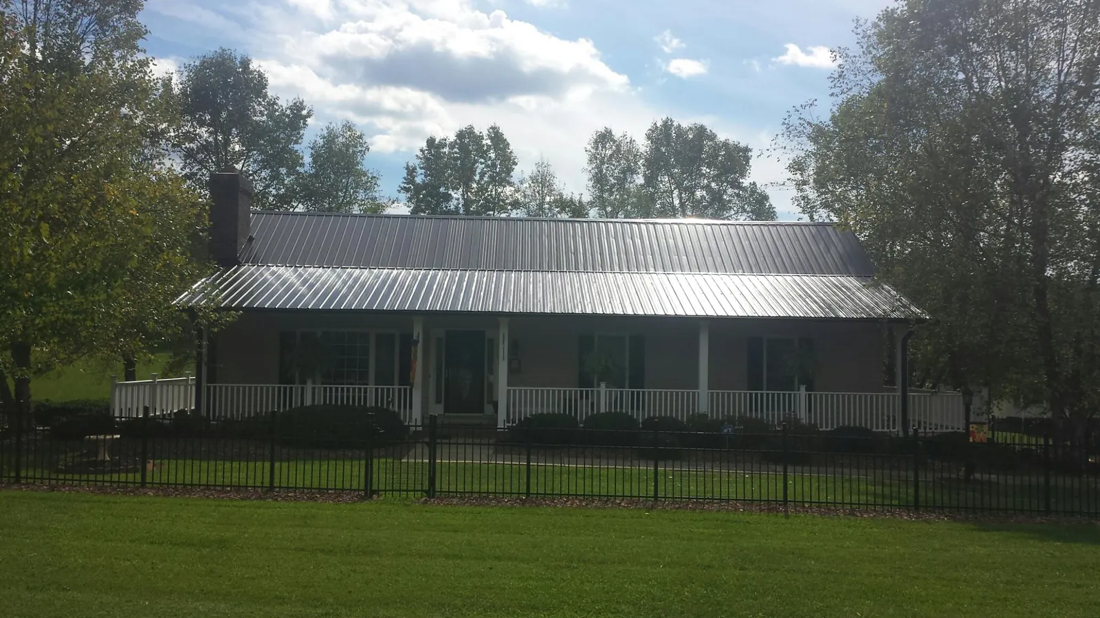 Gray metal roof on a brick ranch with a full width front porch — Gutter Guard Installation work by our crew in Elvaston
